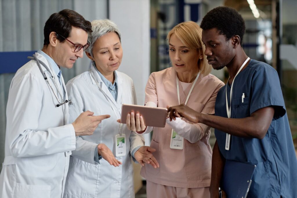 Group of doctors in white coats with two nurses in pink and blue scrubs - Stroudwater